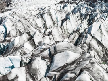 İzlanda 'da, volkanik küllerle çizilmiş pürüzlü buz sırtları, karmaşık desenleri ve engebeli araziyi gösteren bir buzulun hava manzarası..