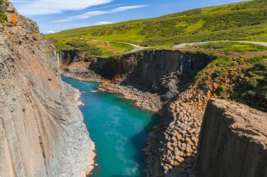 İzlanda 'daki Studlagil Kanyonu' nda geometrik bazalt sütunlar, canlı bir turkuaz nehir ve çarpıcı bir doğal manzara yaratan yemyeşil çevre bulunmaktadır..
