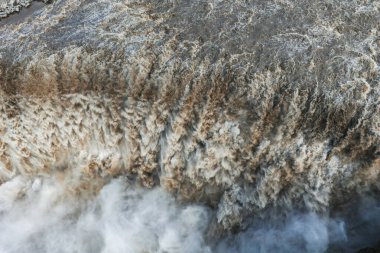 İzlanda 'daki Dettifoss şelalesinin hava görüntüsünü kapatın. Güçlü akıntıdan yükselen sisli, çalkantılı kahverengi ve beyaz çağlayan su sergiliyor..
