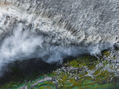 İzlanda 'daki Dettifoss şelalesinin hava perspektifi. Sis dolu sular, canlı yeşil yosunlar ve çevreleyen engebeli araziler..