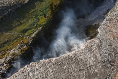 İzlanda 'daki kayalıklar, yosunlar ve kayalık arazilerle çevrili bir kanyona düşen buzul suyuyla Dettifoss şelalesinin dramatik hava manzarası..