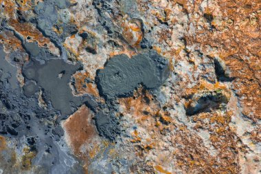 Kabaran çamur tencereleri, grimsi mavi havuzlar ve canlı mineral yataklarıyla turuncu kahverengi arazi içeren İzlanda jeotermal bölgesinin hava görüntüsü.
