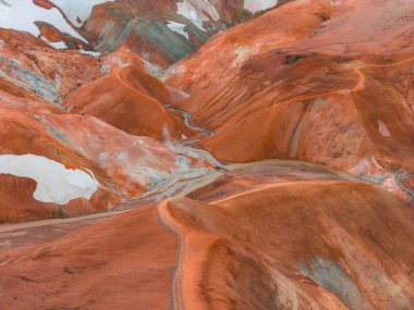 İzlanda 'nın Gökkuşağı Dağları' nın canlı çok renkli rhyolite tepeleri, kırmızı, turuncu ve yeşil renkli kar bantları ve dolambaçlı bir patika.