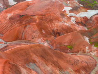 Kırmızı, turuncu ve kahverengi renkleri, yeşil yosunları, kar yosunları, dolambaçlı yolları ve uçsuz bucaksız arazideki küçük figürlerle dolu çok renkli rhyolite tepeleri..