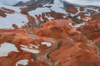 Canlı turuncu, kırmızı ve kahverengi rhyolite dağlarında kar yamaçları ve Landmannalaugar, İzlanda 'da dolambaçlı bir patika var..