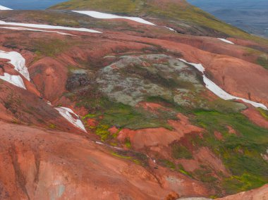 İzlanda 'nın Gökkuşağı Dağları' nın kırmızı, turuncu ve yeşil renkleri dağınık kar ve verimli bitki örtüsü ile dolu renkli arazisi jeotermal aktiviteleri vurguluyor..