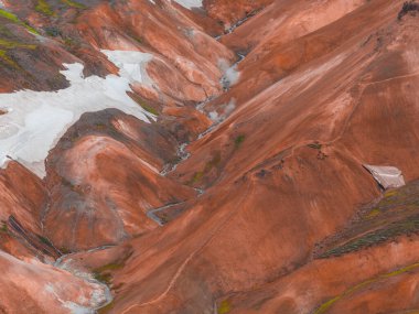 Canlı kırmızı, turuncu ve kahverengi rhyolite tepeleri. Kar yamaçları, jeotermal buhar ve Landmannalaugar, İzlanda 'da dönen bir dere..