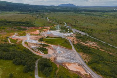 İzlanda 'da kaynayan gayzerler, kaynayan kaplıcalar, turuncu ve beyaz mineral yatakları ve dönen bir nehir bulunan jeotermal bir bölgenin havadan görüntüsü..