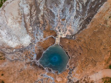 İzlanda 'daki jeotermal kaplıcalarda çok renkli mineral yatakları, buharlı çatlaklar ve karmaşık jeolojik desenlerle çevrili parlak mavi bir havuz var..