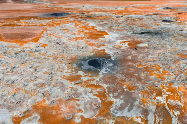 İzlanda 'da turuncu ve beyaz mineral yataklarının, dumanı tüten çamur tencerelerinin, fümerollerin ve çorak, desenli bir manzaranın yer aldığı bir jeotermal alanın havadan görünüşü..