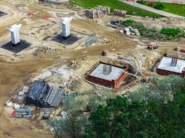 Riga 'dan Jelgava yoluna büyük ölçekli yol kavşağı güncellemesi, beton sütunlar, ağır ekipmanlar, toprak ve çevreleyen yeşillikler.