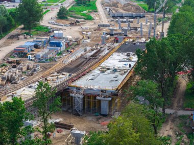 Letonya 'da kısmen tamamlanmış üst geçidi, iskelesi, beton sütunları, makineleri ve yeşil çevresi olan büyük ölçekli yol inşaatı.
