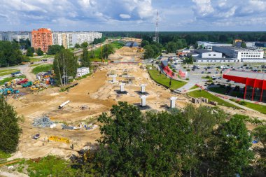 Riga 'dan Letonya' daki Jelgava yoluna kadar büyük ölçekli yol inşaatı. Özellikler köprü sütunları, ağır makineler, konut binaları ve yeşil alanlar.