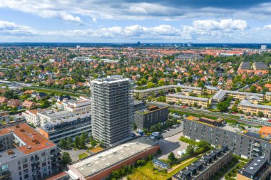 Kopenhag, Danimarka 'nın havadan görünüşü, iskelesi, kırmızı kiremitli çatıları, yeşil alanları ve uzak bir enerji santrali olan yüksek bir bina gösteriyor..