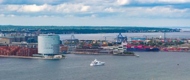 Kopenhag, Danimarka 'nın hava manzarası, modern silindirik bir bina, vinçlerle ve konteynırlarla dolu yoğun bir liman, bir yat ve yeşil manzaralar gösteriyor..