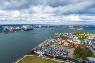 Kopenhag, Danimarka 'da bir rıhtım manzarası, Reffen gıda mahkemesi bölgesi, bir kaykay sahası, renkli koltuklar, küçük yapılar, botlar ve yakınlardaki sanayi binaları.