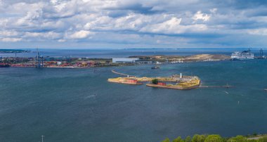 Danimarka, Kopenhag 'ın hava manzarası, güçlendirilmiş bir adayı, sakin suları, bir yolcu gemisini, nakliye konteynerlerini, vinçleri ve bulutlu gökyüzünü gösteriyor..