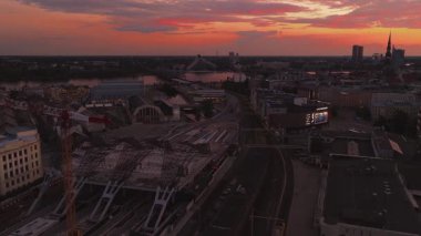 Gün batımında Riga, Letonya 'nın hava görüntüsü. Şehir manzarasında Riga saat kulesi, tren istasyonu, tarihi kuleler, sokaklar ve aydınlatma işaretleri yer alıyor..