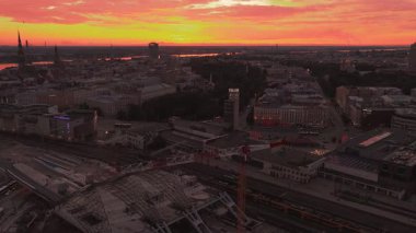 Gün batımında Riga, Letonya 'nın panoramik manzarası. Daugava Nehri, şehrin ışıkları eski şehirle modern mimariyi aydınlatırken sıcacık renkleri yansıtıyor..