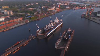 Gün batımında Riga, Letonya 'da bir tersane, kuru rıhtımlar, vinçler, endüstriyel binalar ve gün batımının canlı renklerini yansıtan sakin su.