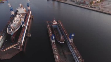 Riga, Letonya 'da bir tersane, kuru rıhtım, hareket halindeki vinçler ve hareket eden işçiler. Endüstriyel çevrelerle altın saat boyunca yakalandılar..