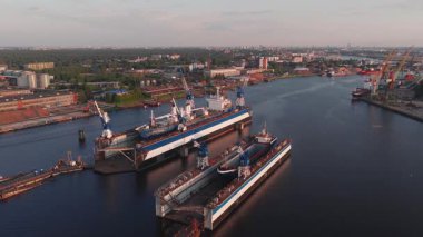 Gün batımında Letonya Riga 'da bir tersane. Büyük gemiler kuru rıhtımlarda demirli, vinçler hareket ediyor ve sanayi bölgesinde hafif hareketlilik var..