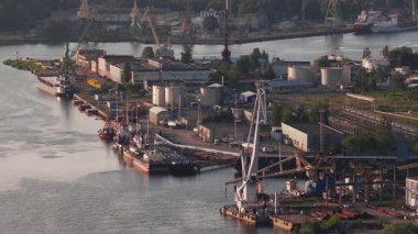 Riga, Letonya 'da bir tersane, vincler hareket halinde, liman gemileri ve Daugava Nehri yakınlarındaki sanayi binaları altın saat boyunca.