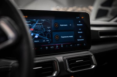 Karbon fiber aksanlı, çift hava menfezli ve Rusça gösterilen bir navigasyon haritalı bir Mercedes AMG sınıfının görüntü ekranı ve göstergesi..