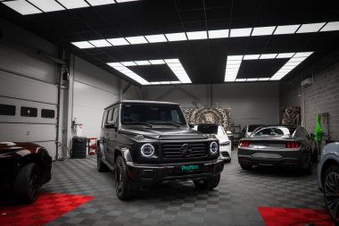 Dairesel farları olan bir Mercedes AMG sınıfı ve kareli zemini olan özel stop lambalı bir Ford Mustang GT 5.0..