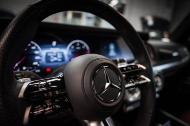 Bir Mercedes AMG sınıfının iç görünümü direksiyonu krom aksanlı, dijital enstrüman kümeli ve detaylı gösterge paneli tasarımlı gösteriyor..