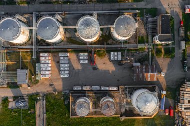 Silindirik tanklar, boru hatları, araçlar ve çevreleyen yeşil ve asfalt alanların bulunduğu Riga, Letonya 'daki bir depolama tesisinin havadan görüntüsü.