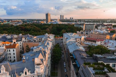 Gün batımında Riga, Letonya 'nın hava manzarasında Jugendstil mimarisi, ağaç kaplı caddeler, bir park, Daugava Nehri ve Riga TV Kulesi yer alıyor..