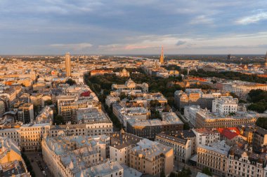 Riga, Letonya 'nın hava manzarası, gün batımında Riga TV Kulesi, Esplanade Parkı, Jugendstil binaları ve altın ışıkla aydınlatılmış modern mimari.