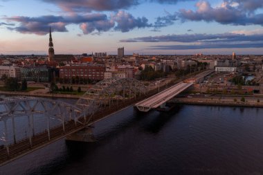Riga, Letonya, Daugava Nehri, kemerli demiryolu köprüsü, St. Peter Kilisesi kulesi ve tarihi ve modern mimarinin karışımı..