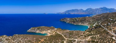 Yunanistan 'ın Girit kentindeki Voulisma Sahili' nde kurak arazi, seyrek bitki örtüsü ve uzak dağları olan Akdeniz ile çevrili bir turkuaz koy..