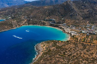 Yunanistan 'ın Girit kentindeki Voulisma Sahili' nin havadan görünüşü, turkuaz sular, engebeli tepeler, seyrek bitki örtüsü ve kıyı şeridi boyunca küçük bir yerleşim yeri ile.