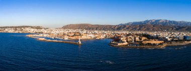 Venedik limanı, deniz feneri, tarihi mimari, modern binalar ve günbatımında engebeli dağları gösteren Girit, Chania 'nın hava manzarası..