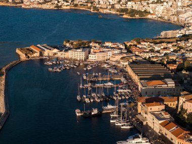 Günbatımında Girit, Chania 'daki Venedik Limanı' nın hava manzarası. Kenetlenmiş tekneler, tarihi binalar, deniz feneri ve derin mavi deniz..