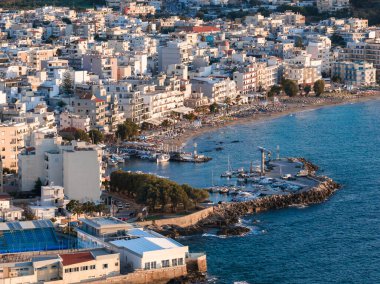 Akdeniz binaları, limanlı tekneleri olan bir marina ve sakin mavi suların üzerinde altın bir günbatımının yer aldığı Chania, Girit, Yunanistan 'ın hava manzarası.