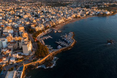 Günbatımında Girit, Yunanistan 'daki Chania' nın hava manzarası. Beyaz ve bej binalar, rıhtımlı tekneleri, taş iskelesi ve sakin mavi bir denizi olan bir marina..