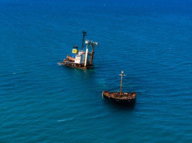 Aralarında paslı Manassa Gülü 'nün de yer aldığı iki gemi enkazı Yunanistan' ın Girit kenti yakınlarındaki turkuaz sularda dinleniyor. Boyalı hunili modern bir gemi de görülebilir..