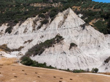 Konik zirveleri, seyrek bitki örtüsü ve Potamida, Girit, Yunanistan 'da saman balyaları olan aşınmış beyaz tortulu kaya tepeleri..