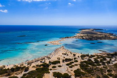 Yunanistan 'ın Girit kentindeki Elafonisi Sahili' nin hava manzarasında turkuaz sular, kumlu bir sahil, dar bir kumsal ve sığ denizde ziyaretçiler görülüyor..