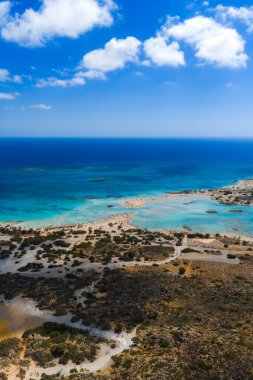 Yunanistan 'ın Girit kentindeki Elafonisi Sahili' nin hava manzarasında turkuaz göller, pembe kum, kayalık arazi, bitki örtüsü ve dağınık ziyaretçiler görülüyor.