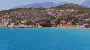 Girit 'teki Voulisma Sahili' nin havadan görünüşü turkuaz suları, kayalık uçurumları, yüzücüleri ve Akdeniz 'deki kuru çalıları gösteriyor..