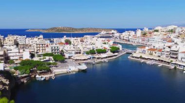 Girit 'teki Agios Nikolaos' un hava görüntüsü marinayı yatlar, beyazlatılmış binalar, dar bir su yolu ve Akdeniz 'i gösteriyor..