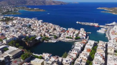 Girit, Agios Nikolaos 'un hava görüntüsü, beyaz ve pastel binaları, tekneli bir marinayı ve kamera tavaları gibi Akdeniz' i gösteriyor..