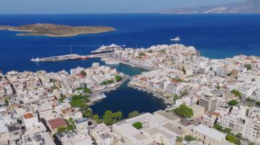 Girit, Agios Nikolaos 'un hava görüntüsü, beyaz binaları, dairesel bir gölü, dar bir kanalı, botları ve akdeniz' i gösteriyor..