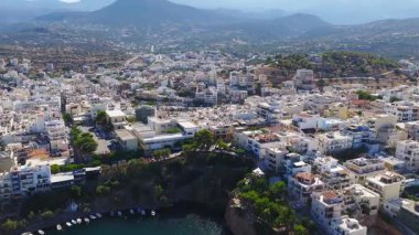Girit, Agios Nikolaos 'un hava görüntüsü, Voulismeni Gölü' nü, beyazlatılmış binaları, tekneli bir marinayı ve hareketli Akdeniz kıyılarını gösteriyor..