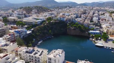 Voulismeni Gölü, kayalık kayalıklar, kenetlenmiş tekneler ve pastel renkli kentsel mimarinin sergilendiği yavaş, süpürgen bir Agios Nikolaos tavası..
